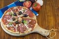 Sliced round pizza and raw vegetables on a wooden table Royalty Free Stock Photo