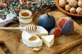 Sliced round of soft ripe creamy French Camembert cheese served with fresh juicy ripe red figs, honey and walnuts on a wooden back Royalty Free Stock Photo