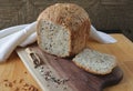 loaf of homemade whole grain bread and a cut slice of bread on a wooden cutting board. Mixture of seeds and whole grains Royalty Free Stock Photo