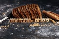 Sliced rye bread on cutting board. Whole grain rye bread with seeds on table and wooden cubes with words gluten free Royalty Free Stock Photo