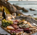 Sliced salami, cheese, bread and wine on the beach. A picnic setting on a beach with a meat charcuterie board and wine for two.
