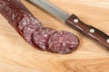 Sliced salami sausage and knife on wooden board