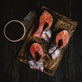 Sliced salmon fish on wooden cutting board with sackcloth and peppercorns on rustic table
