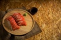 Sliced salmon placing on wooden plate together wasabi radish and shoyu on burlap table by top view