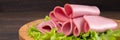 Sliced sausages with salad leaves on the wood background