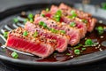 Sliced Seared Tuna Steak with Sesame Seeds and Soy Sauce on Black Ceramic Plate, Gourmet Seafood Dish