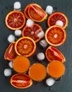 Sliced Sicilian red oranges and orange juice in small glasses on black stone background. Top view Royalty Free Stock Photo