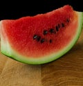 Sliced skib of ripe watermelon on a wooden board on a black background Royalty Free Stock Photo