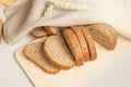 Sliced slices of coarse rye bread on a wooden cutting Board with a linen cloth and rye ears, the concept of a bakery and small Royalty Free Stock Photo