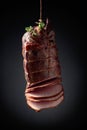 Sliced smoked gammon with thyme branches on a black background