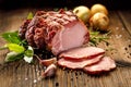 Sliced smoked gammon on a wooden table with addition of fresh herbs and aromatic spices.