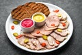 Sliced smoked meat and salami with sauce on a white plate. Royalty Free Stock Photo