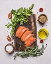 Sliced smoked salmon with parsley and rosemary, oil and spices on a cutting board wooden rustic background top view Royalty Free Stock Photo