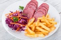 Sliced smoked veal fillet, french fries and red cabbage salad Royalty Free Stock Photo