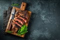 Sliced steak ribeye, grilled with pepper, garlic, salt and thyme served on a wooden cutting Board on a dark stone background. Top