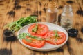 Sliced tomatoes and arugula spices salad. In a white bowl on a wooden table. Selective focus Royalty Free Stock Photo