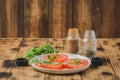 sliced tomatoes and arugula spices salad. In a white bowl on a wooden table. Selective focus Royalty Free Stock Photo