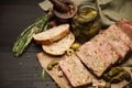 Sliced Traditional French terrine covered with bacon on dark wooden background