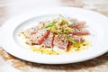 sliced tuna steak with green onions and sesame oil on white plate