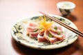 sliced tuna steak revealing pink center, with chopsticks on side