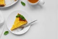 Sliced upside down pineapple cake decorated green leaves with cup of tea on white table. Summer tropical dessert. Top view. Copy Royalty Free Stock Photo