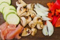 Sliced vegetables on a cutting wooden board: mushrooms, zucchini, red bell pepper Royalty Free Stock Photo