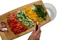 Sliced vegetables: tomato, cucumber, paprika, green onion, dill and parsley sprinkle from cutting board to glass bowl Royalty Free Stock Photo