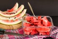 Sliced watermelon in glass container with black seeds on black background with watermelon peels Royalty Free Stock Photo