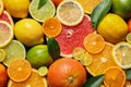 Sliced and whole citrus fruits with leaves as background