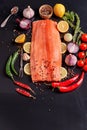 Sliced whole filet with green and red chili peppers, lemon, peas, garlic, cherry tomatoes on a sprig, on ions and rosemary Royalty Free Stock Photo