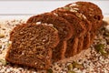 Sliced whole-grain bread, sprinkled with grains on wooden board. Close-up, macro Royalty Free Stock Photo