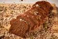 Sliced whole-grain bread, sprinkled with grains on a wooden board. Close-up, macro Royalty Free Stock Photo