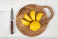 Sliced and whole lemons on cutting board with a knife next to it in top view Royalty Free Stock Photo