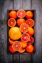 Sliced and whole ripe juicy blood oranges and grapefruit in the box on wooden background. Royalty Free Stock Photo