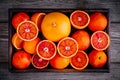 Sliced and whole ripe juicy blood oranges and grapefruit in the box on wooden background. Royalty Free Stock Photo