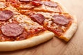 Sliced whole salami pizza on wooden table Royalty Free Stock Photo