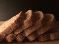 Sliced wholemeal bread on wooden cutting board with black background