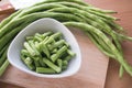 Sliced yard long bean vegetable on the white dish and wooden block.