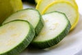 Sliced yellow and green zucchini`s on a white plate sitting on a kitchen table waiting to be consumed Royalty Free Stock Photo