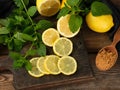 sliced yellow lemons on a brown wooden board, next to it lies a bunch of green mint Royalty Free Stock Photo