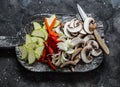 Sliced zucchini, mushrooms, sweet paprika, onions on a rustic chopping board on a dark background, top view. Raw food ingredients Royalty Free Stock Photo