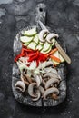 Sliced zucchini, mushrooms, sweet paprika, onions on a rustic chopping board on a dark background, top view. Raw food ingredients Royalty Free Stock Photo
