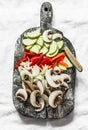 Sliced zucchini, mushrooms, sweet paprika, onions on a rustic chopping board on a light background, top view. Raw food ingredients Royalty Free Stock Photo