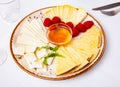 Slices of artisanal cheeses on plate with raspberries and honey