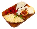 Slices of artisanal cheeses on wooden board with raspberries and honey