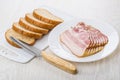 Slices of bacon in plate, bread on cutting board, knife Royalty Free Stock Photo