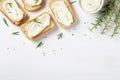 Baguette pieces with tofu cream cheese and rosemary on a white table, viewed from above. Room for text Royalty Free Stock Photo