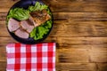 Slices of baked pork meat and lettuce leaves on a black plate. Top view Royalty Free Stock Photo