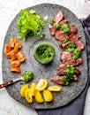 Slices of beef steak with chimmichuri sauce on gray stone plate Royalty Free Stock Photo