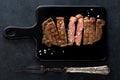 Slices beef Steak Ribeye on a black cutting board and meat fork Royalty Free Stock Photo